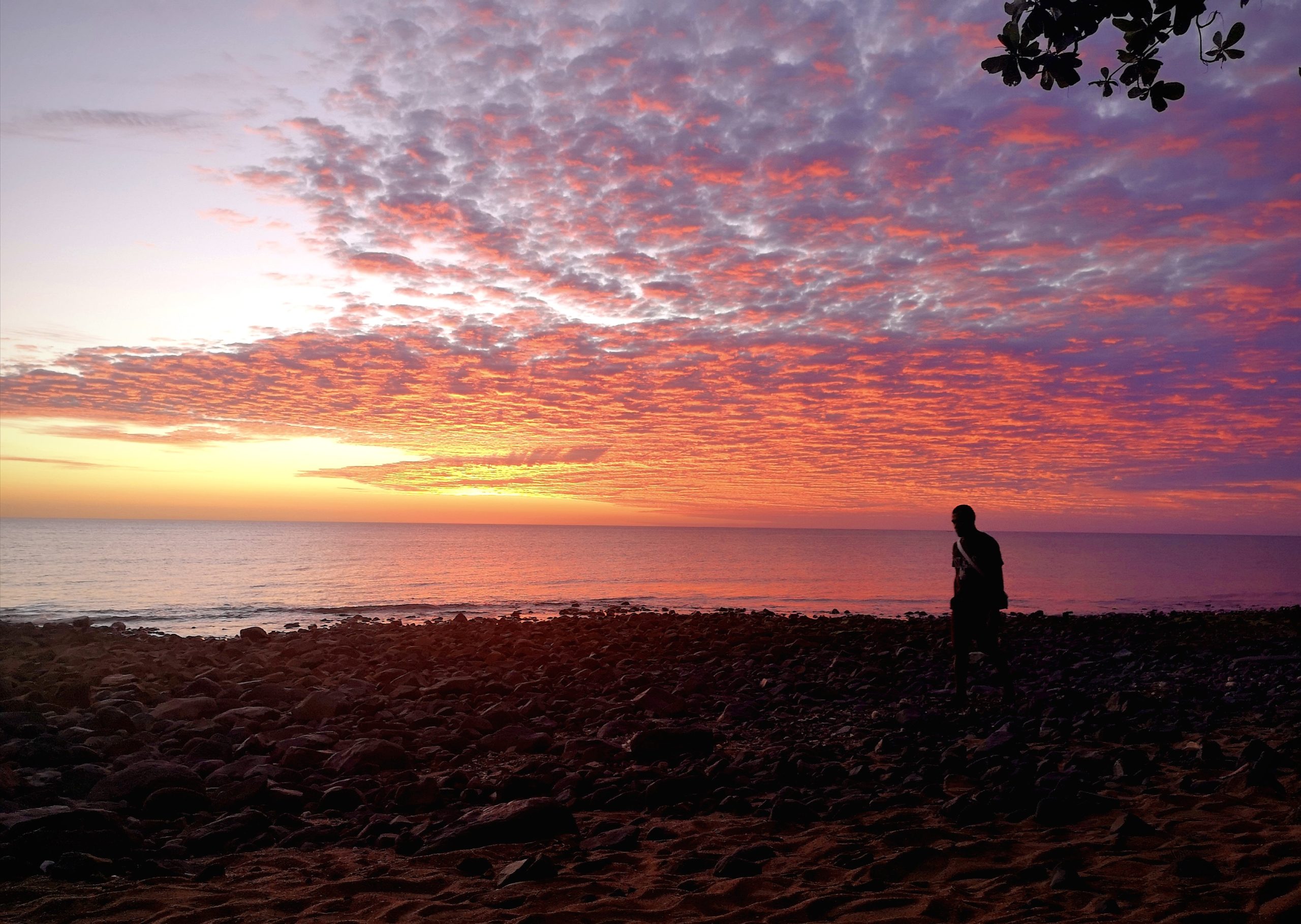 Sur la plage du village de Bouéni, un homme marche face au coucher de soleil